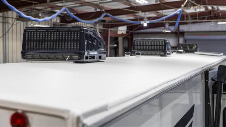 RV roof with multiple rooftop air conditioning units inside an RV service facility.