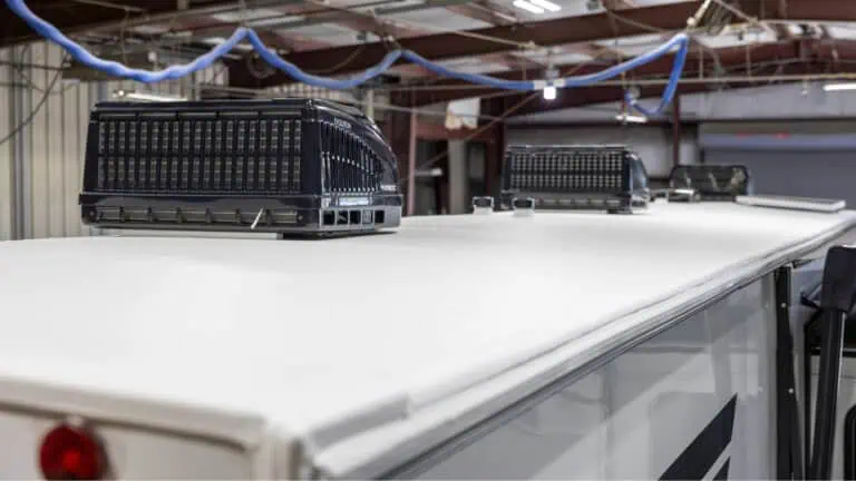 RV roof with multiple rooftop air conditioning units inside an RV service facility.